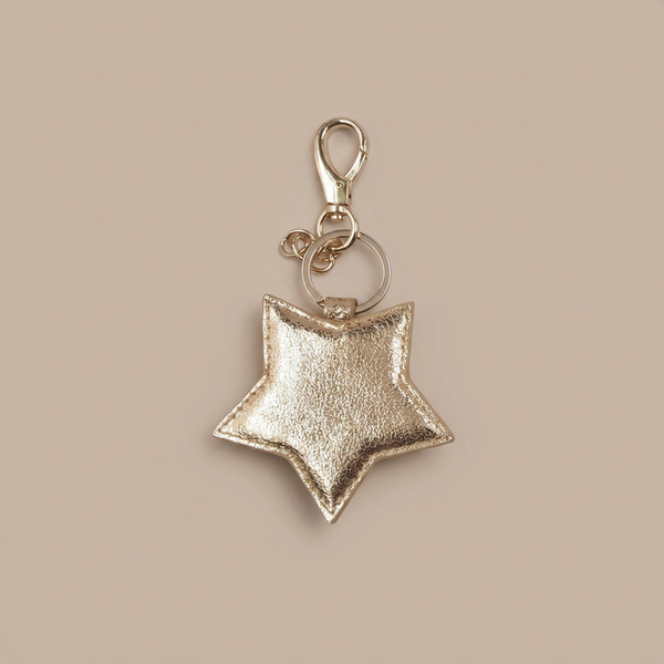 Gold leather star keyring on a neutral taupe-beige background