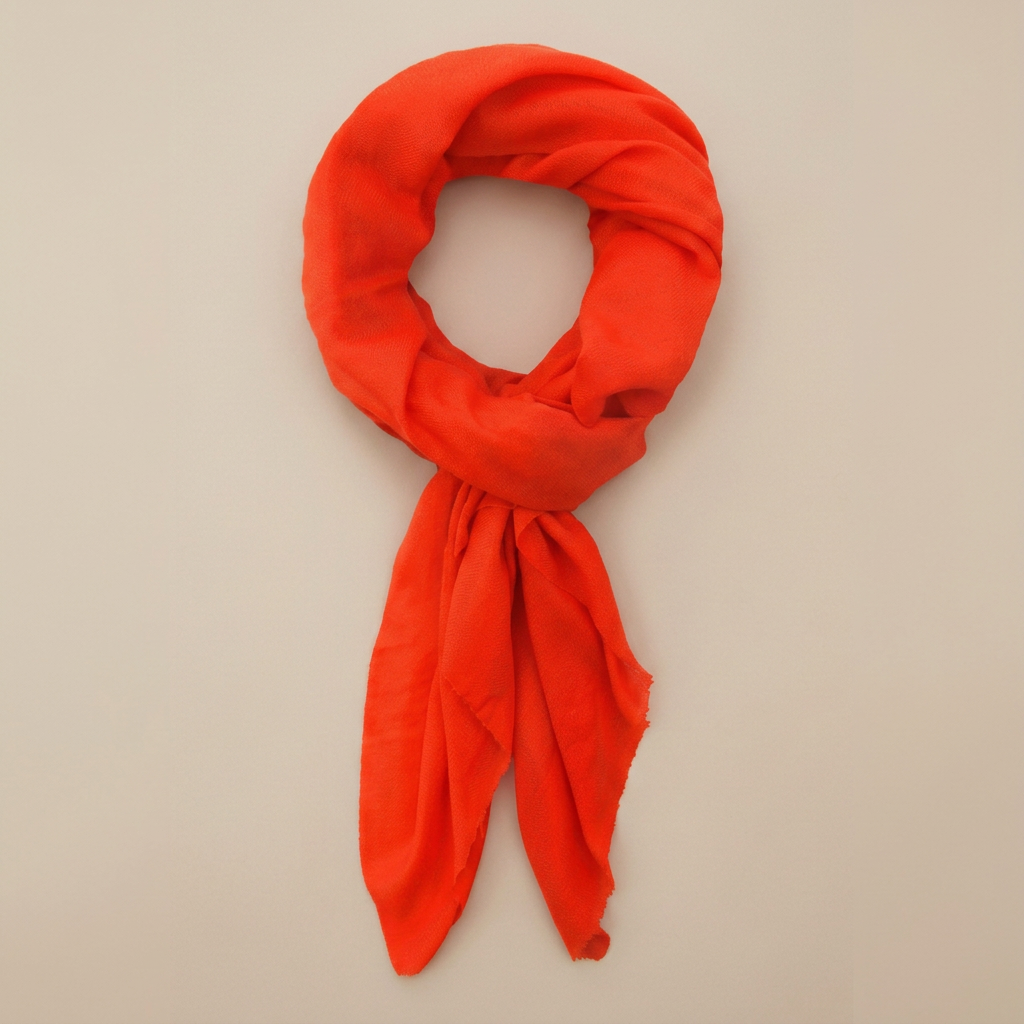 Neon orange cashmere scarf on an edge-to-edge warm beige background
