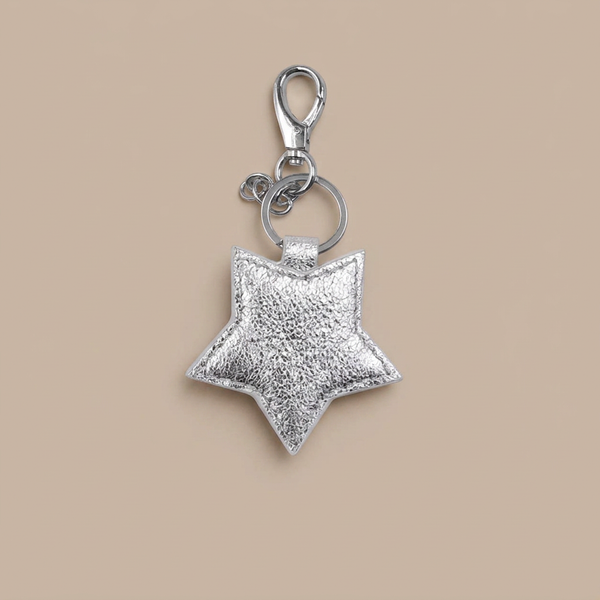 Silver leather star keyring on a neutral taupe-beige background