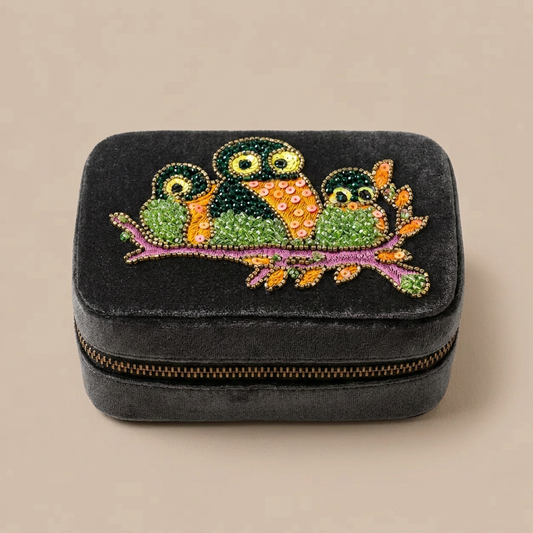 Dark grey jewellery case with three beaded owls on a warm beige background
